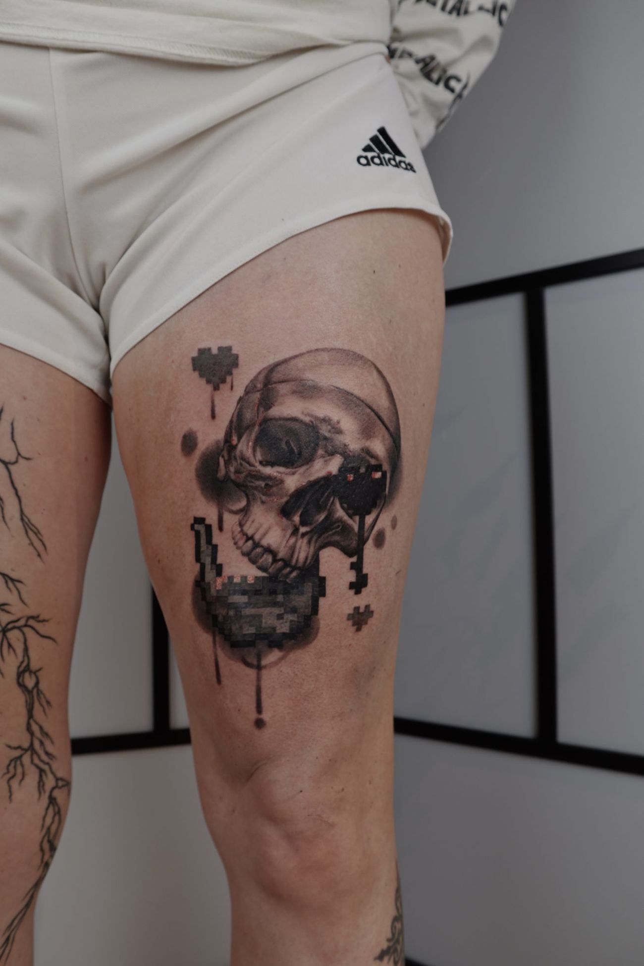 a person's thigh with a tattoo of a skull and pixels